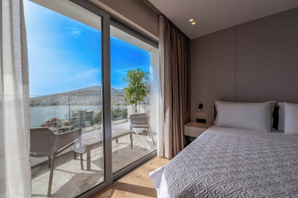 A hotel room with a large sliding glass door leading to a balcony with a city view.