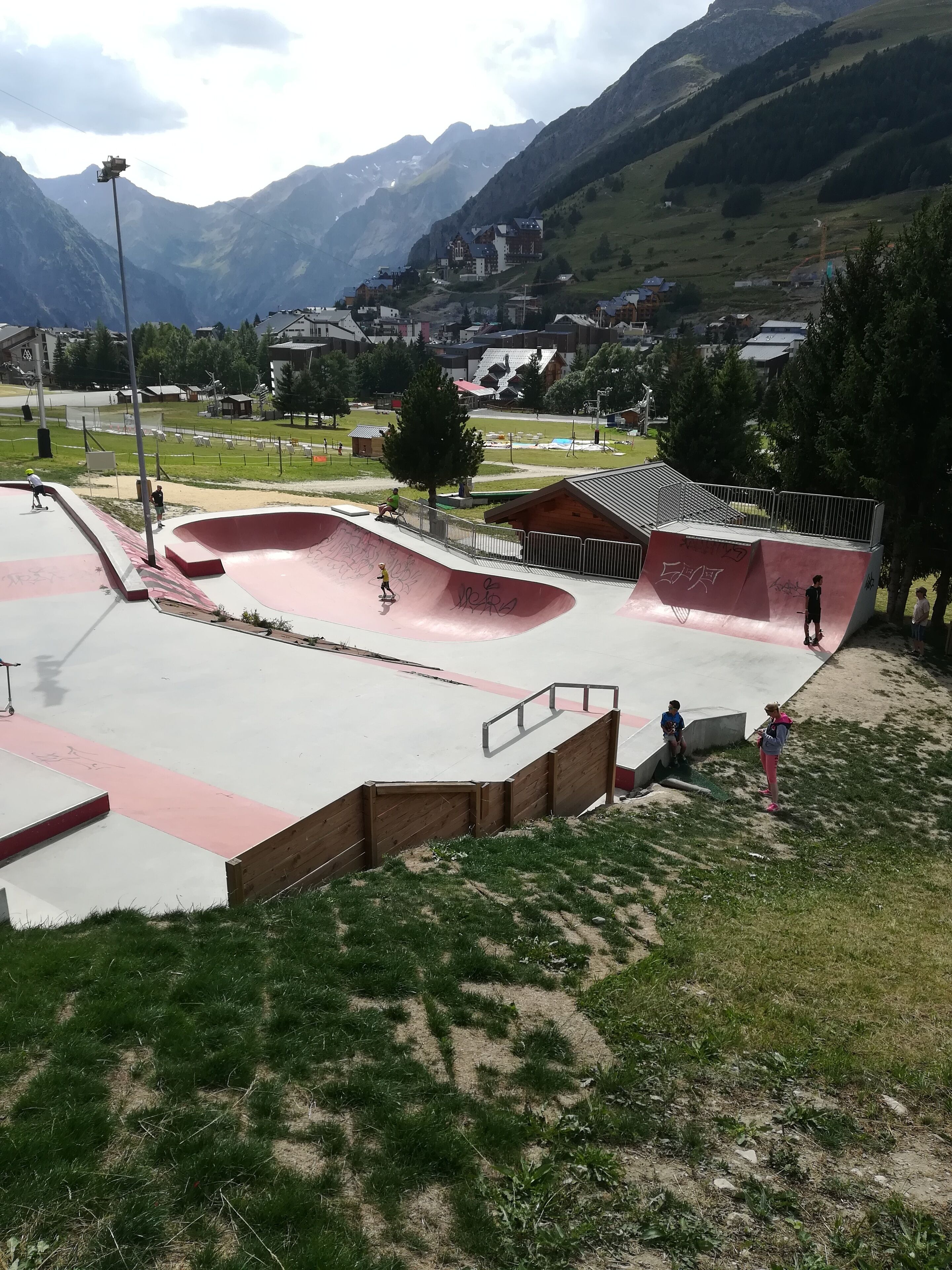 A skate park with various ramps and a surrounding grassy area.