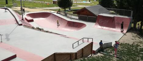 A skate park with various ramps and a surrounding grassy area.