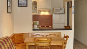A compact kitchen with a dining table and chairs, a microwave, and a refrigerator. - T2 rent at the foot of the slopes - Les Deux Alpes - 38m2 + balcony (Les Deux-Alpes)