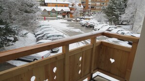 A balcony with a wooden railing and heart-shaped cutouts, overlooking a parking lot with several cars and a building with a sign reading "ARLOT" in the background. - T2 rent at the foot of the slopes - Les Deux Alpes - 38m2 + balcony (Les Deux-Alpes)