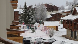 A snowy residential area with wooden buildings, parked cars, and a staircase. - T2 rent at the foot of the slopes - Les Deux Alpes - 38m2 + balcony (Les Deux-Alpes)