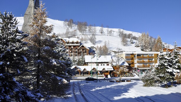 A snow-covered mountain town with a prominent church spire, a ski resort, and a hotel with multiple balconies. - T2 rent at the foot of the slopes - Les Deux Alpes - 38m2 + balcony (Les Deux-Alpes)