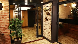 Vestíbulo de hotel con pared de ladrillo, puerta de cristal y planta en maceta.