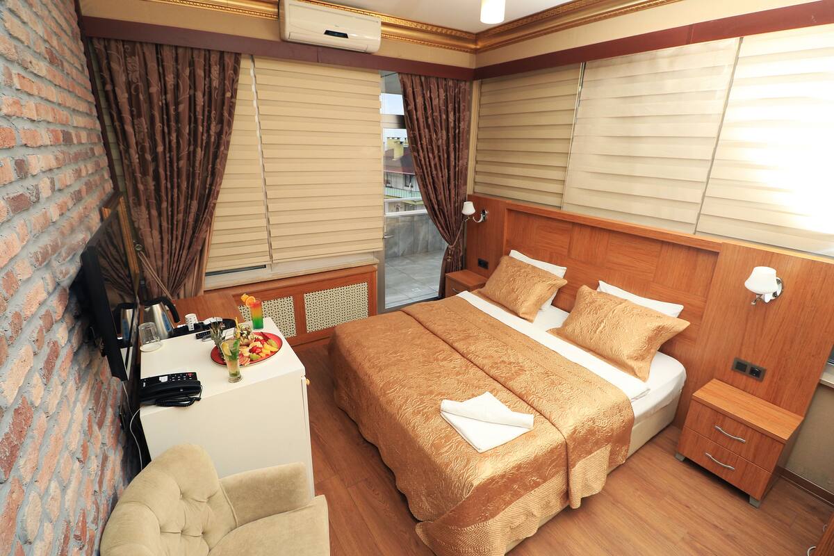 A hotel room with a bed, bedside table, and a desk with a chair.