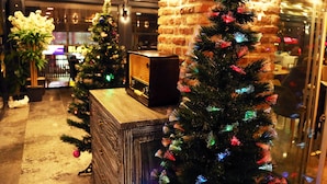 Un vestíbulo con un pilar de ladrillo, un mostrador de recepción de madera y dos árboles de Navidad iluminados.