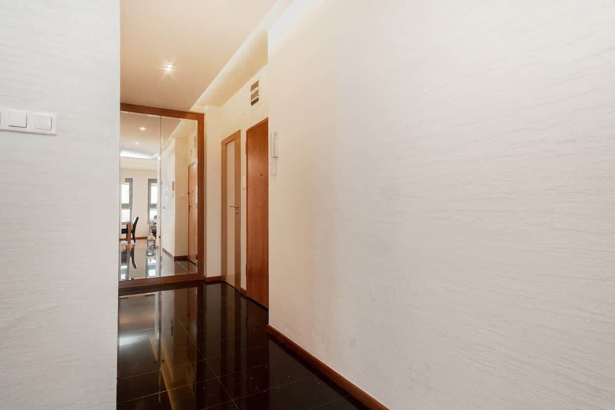 A hallway with a glossy black floor, light-colored walls, and wooden doors.