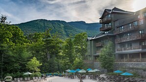 A resort with a swimming pool, lounge chairs, and a mountain backdrop.
