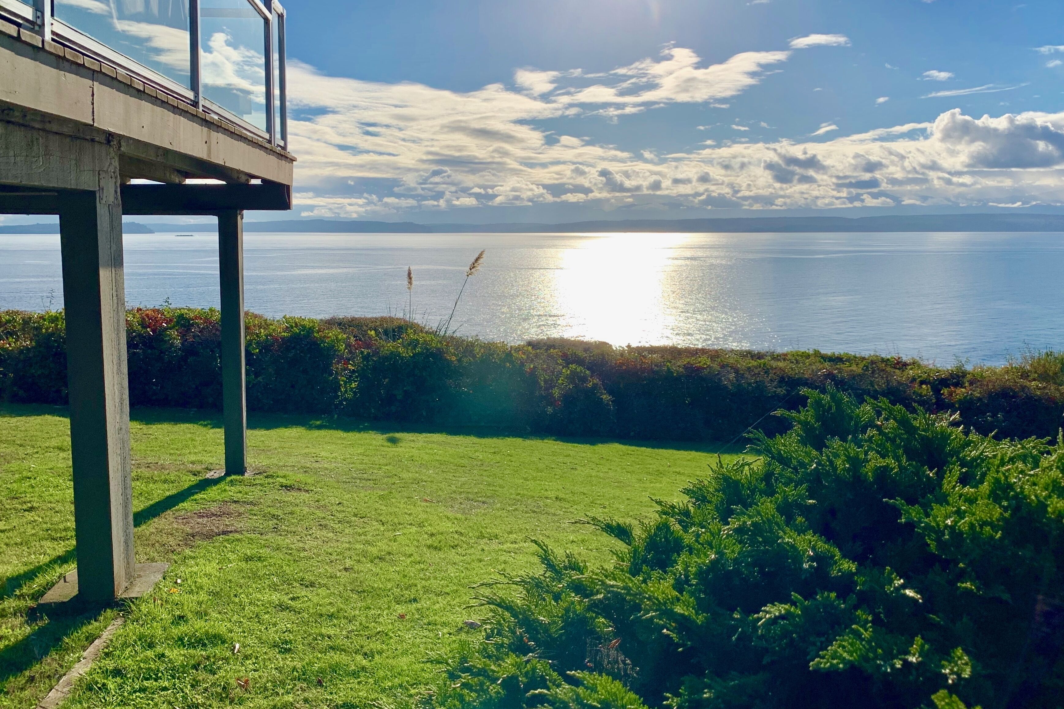 A coastal view with a grassy area, a concrete structure, and a clear sky.