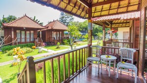 Un espacio al aire libre techado con mobiliario de madera y vistas a un jardín.