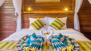 Una cama con dosel, almohadas y una presentación de toallas.