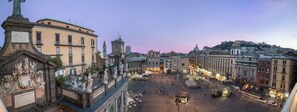 A historic square with classical architecture, including statues and ornate facades, surrounded by buildings with balconies and street lamps. - Rinuccini Relais (Naples)