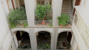 A multi-level courtyard with balconies, each with potted plants.