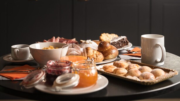 A breakfast tray with pastries, a mug, and a bowl of cereal on a table.