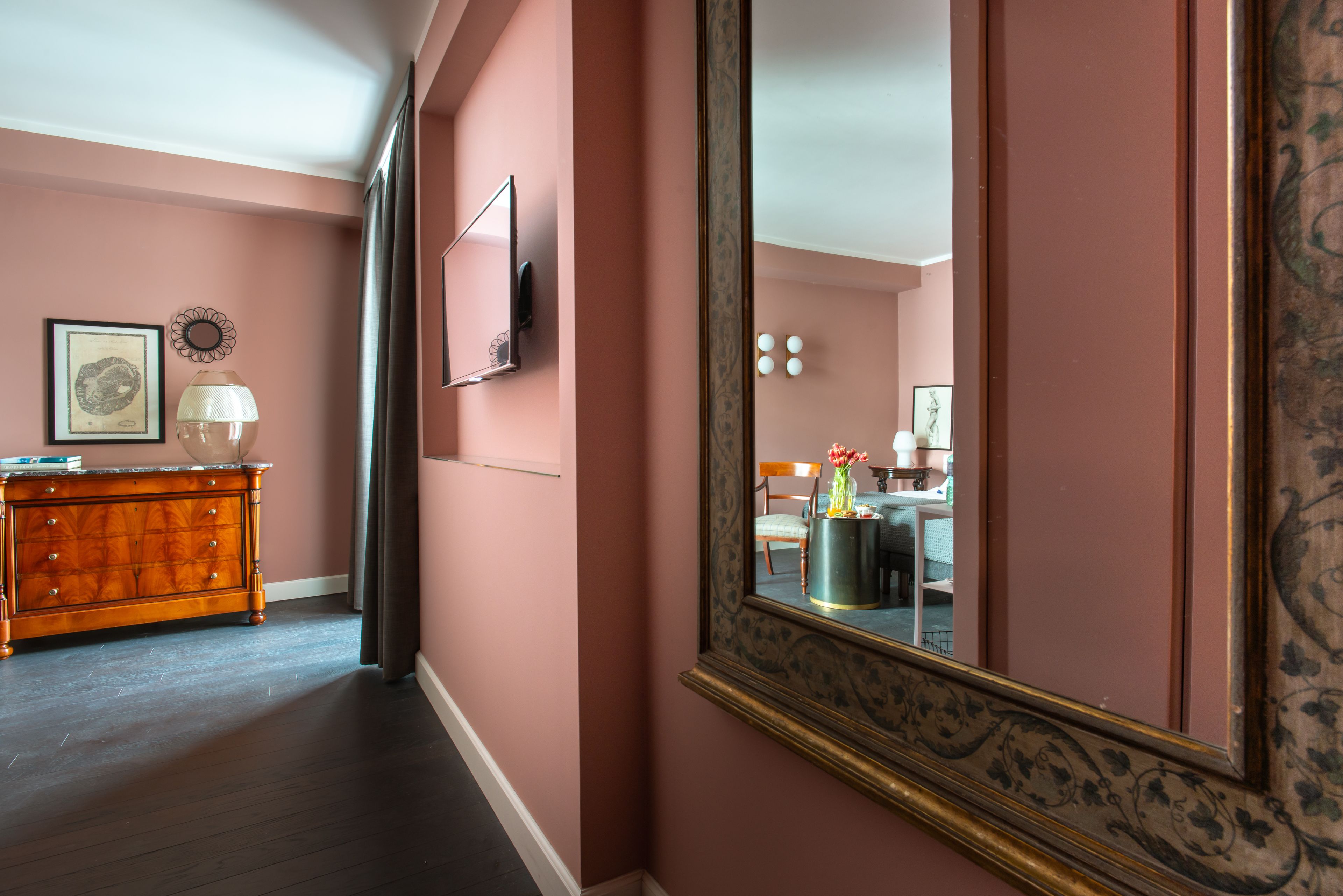 A room with a large mirror, a dresser, and a framed picture on the wall.