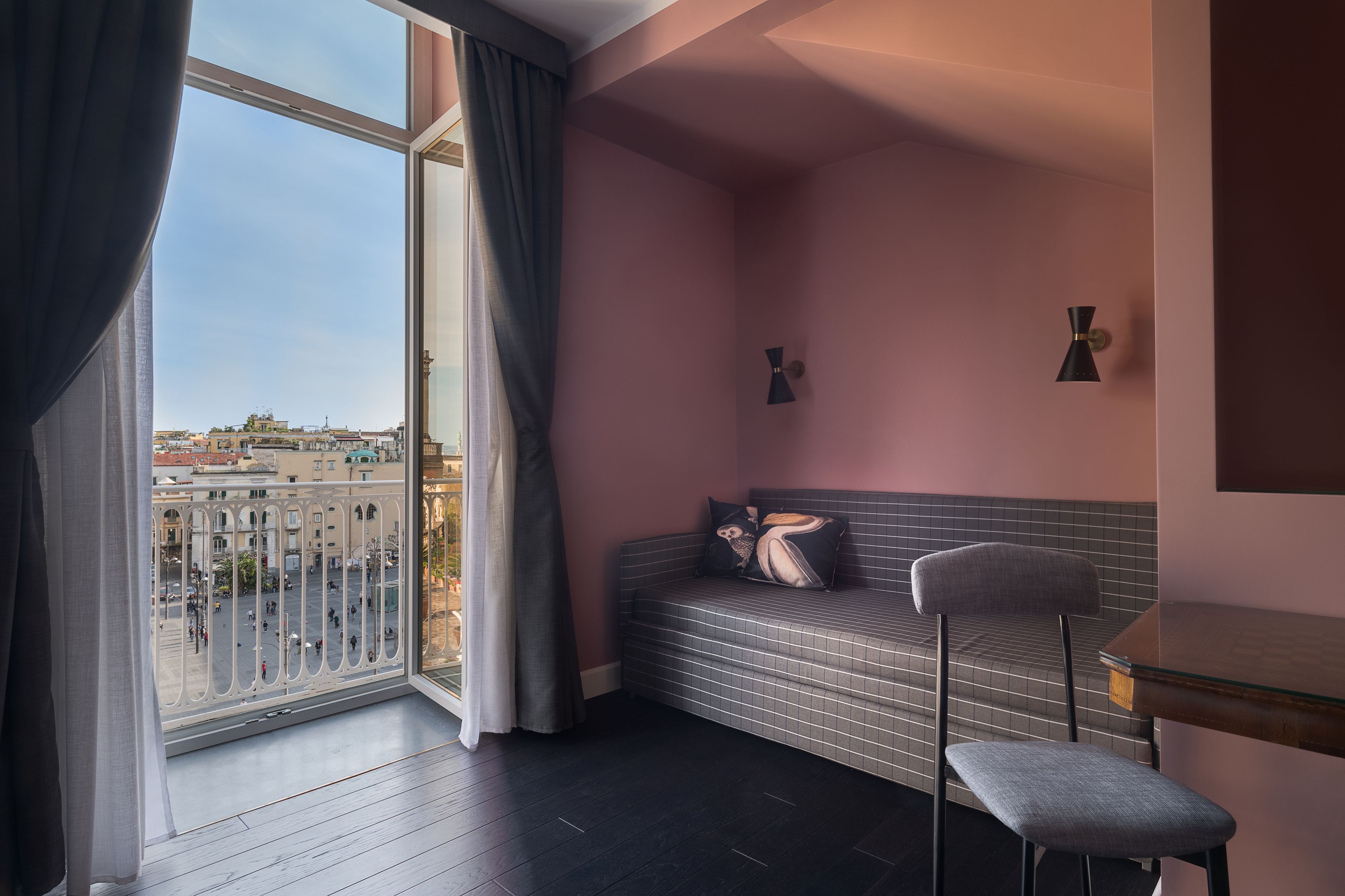 A room with a large window, a sofa, a chair, and a small table.