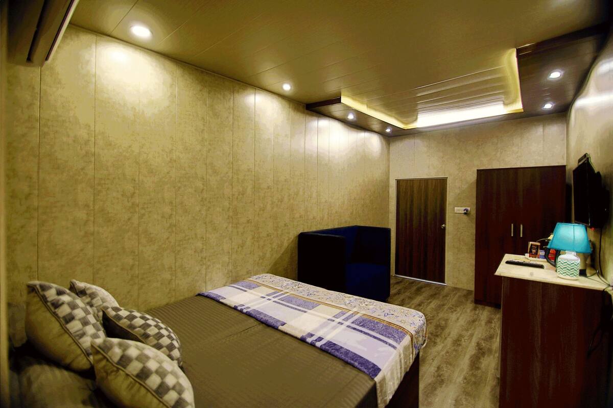 Une chambre d’hôtel comprenant un lit, un bureau avec une lampe, une armoire et un miroir.