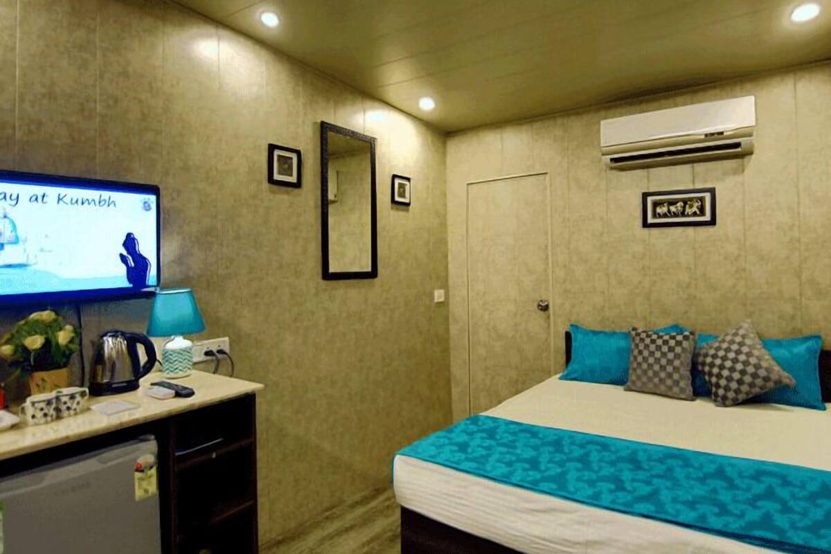 Une chambre d’hôtel équipée d’un lit, d’un bureau, d’une télévision et d’un climatiseur fixé au mur.