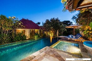 Un espace piscine doté d’une terrasse carrelée, de chaises longues et d’un parasol.