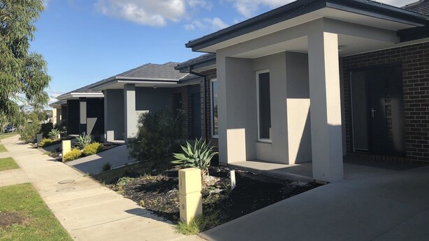 A row of modern houses with a uniform architectural style, featuring flat roofs and a mix of brick and stucco exteriors.