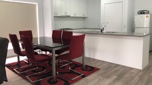 A modern kitchen with white cabinets, a black countertop, and a red rug.