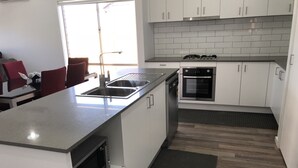 A modern kitchen with white cabinets, a stainless steel sink, a built-in oven, and a microwave.