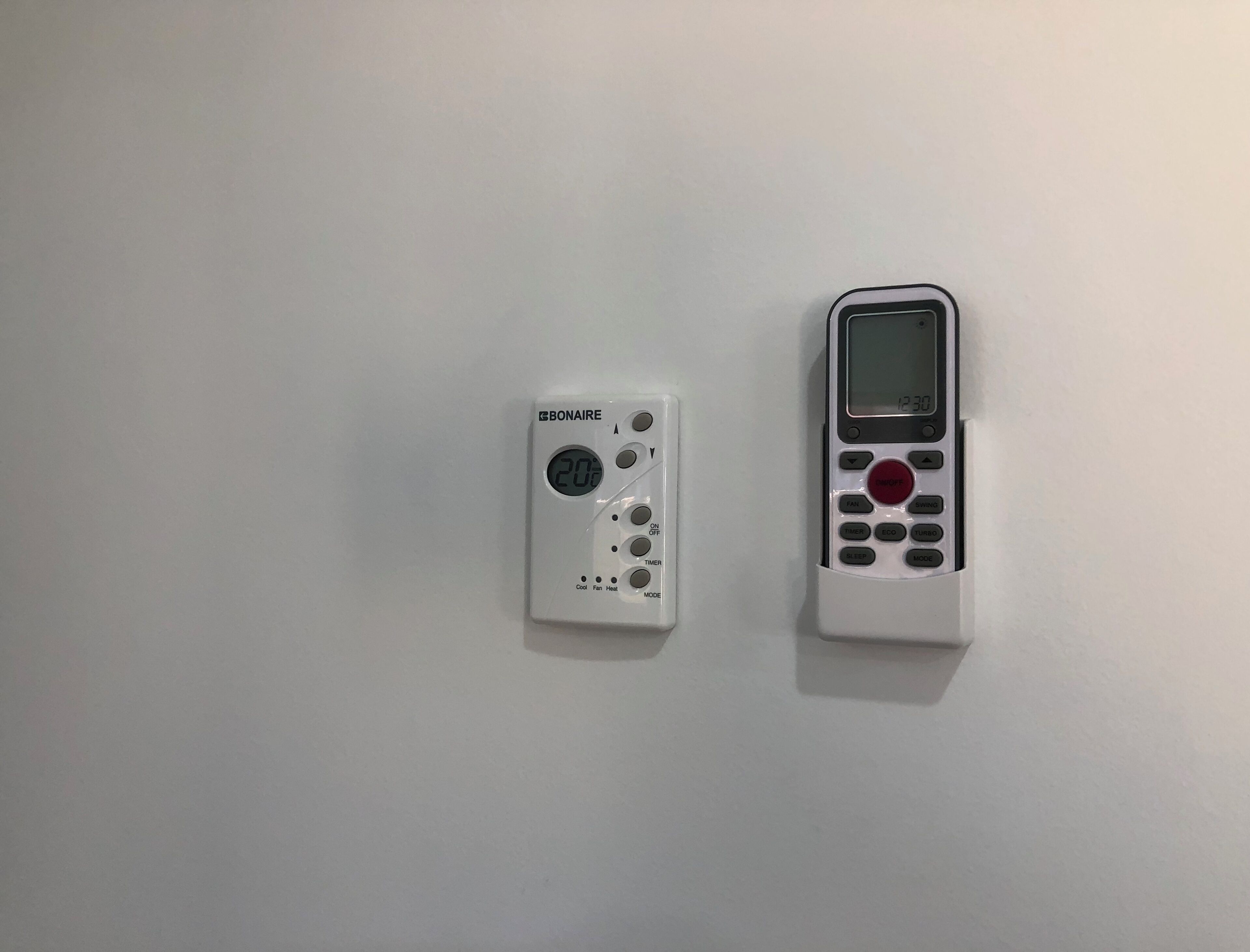 Zwei weiße elektronische Geräte, eines mit digitalem Display und Tasten, das andere mit Tastatur und Bildschirm, auf einer schlichten Oberfläche.