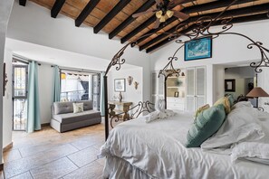 A bedroom with a large bed, a sofa, and a balcony.