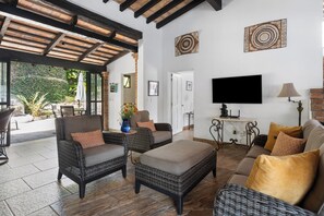 A spacious living area with wicker furniture, a flat-screen TV, and decorative wall art.