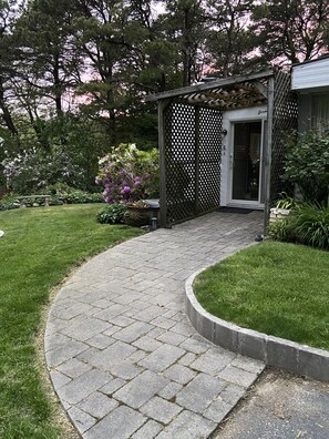 Stroll along the garden pathway to the entrance, surrounded by lush greenery and vibrant flowers.