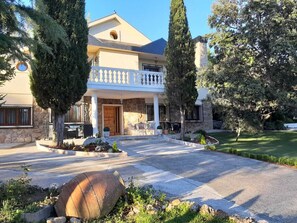 Una casa de dos pisos con fachada de piedra, un balcón y un césped bien cuidado.