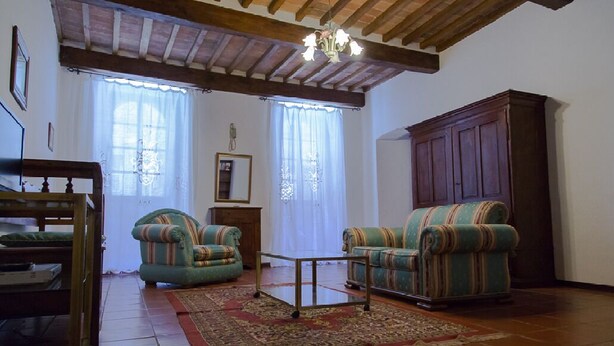 A living room with two striped armchairs, a wooden coffee table, and a large cabinet. - Historic house in the center of Cortona (Cortona)