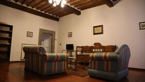 A living room with two striped armchairs, a wooden coffee table, and a television. - Historic house in the center of Cortona (Cortona)