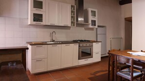 A kitchen with white cabinets, a stainless steel sink, a gas stove, and a built-in oven. - Historic house in the center of Cortona (Cortona)