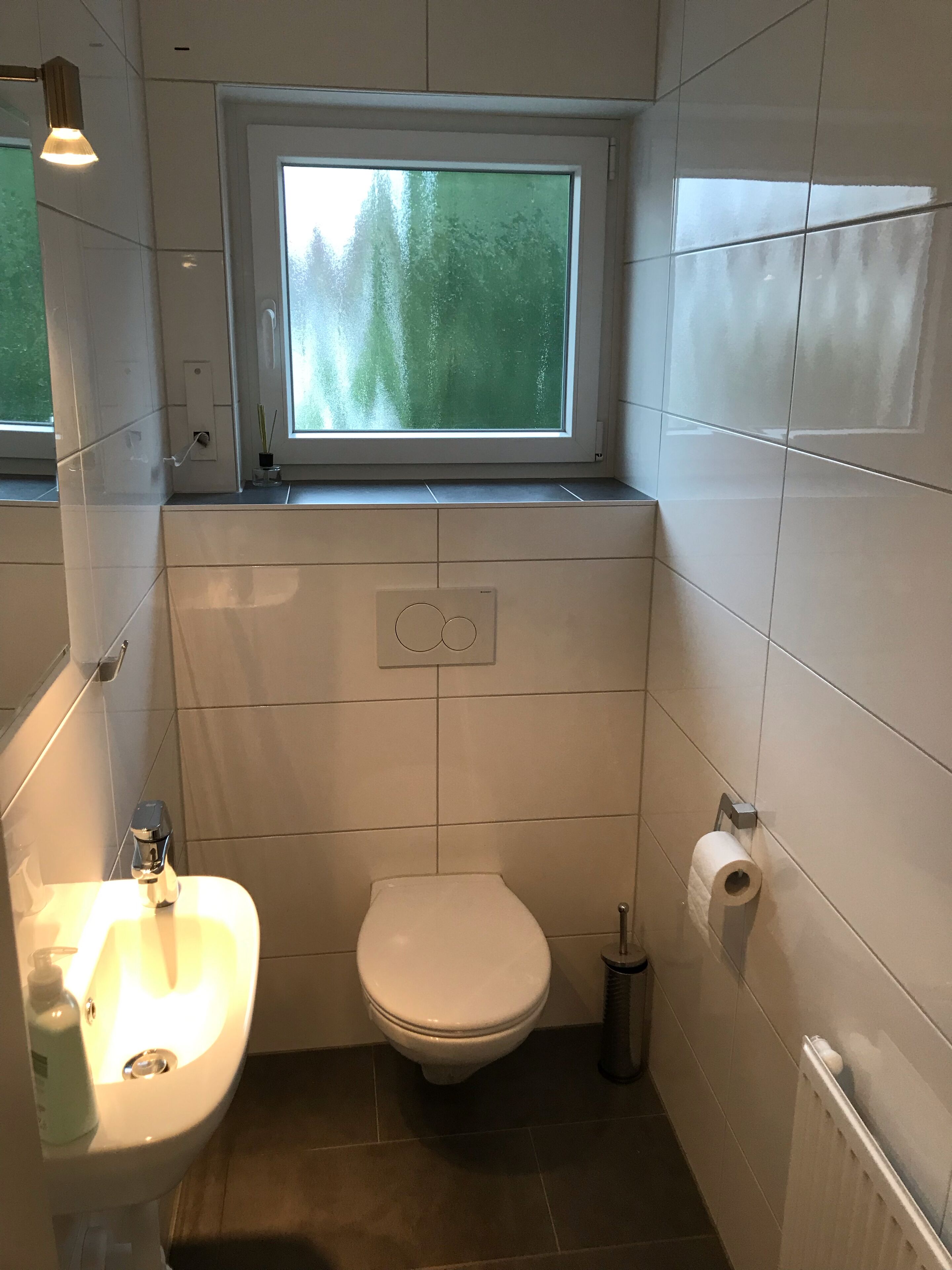 Ein kleines Badezimmer mit Toilette, Waschbecken und Fenster.