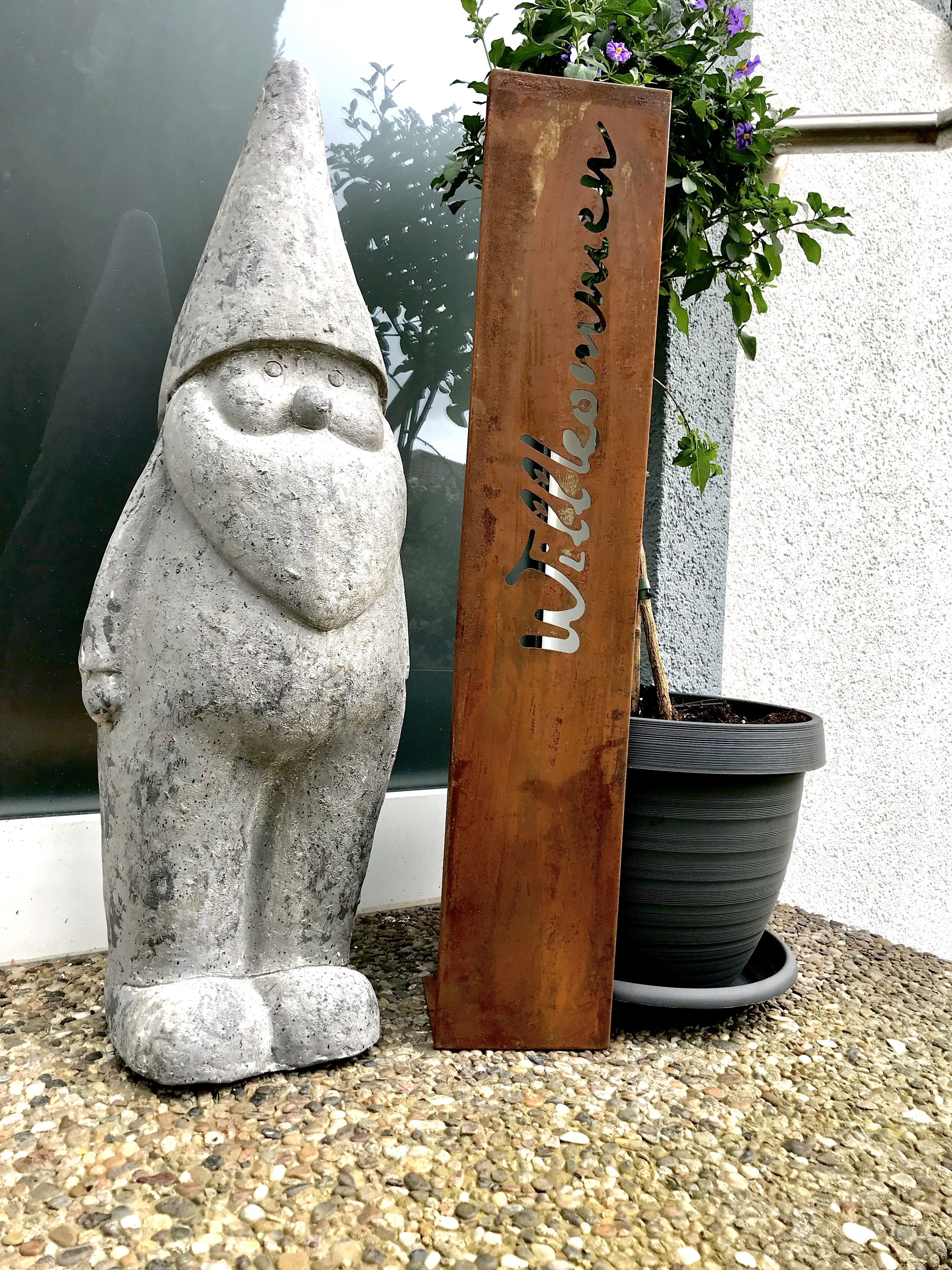 A garden gnome statue and a wooden sign with the name "Witherow" beside a potted plant.