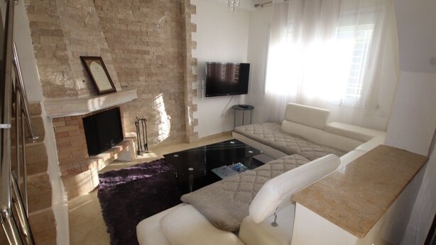Un salon moderne avec une cheminée, un téléviseur à écran plat fixé au mur, un canapé et une table basse.