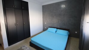 Une chambre à coucher avec un lit, une armoire et un mur gris à texture.