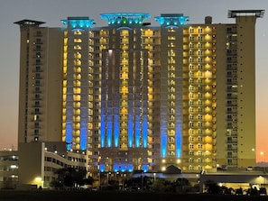 A high-rise building with multiple floors, each illuminated with warm interior lighting.