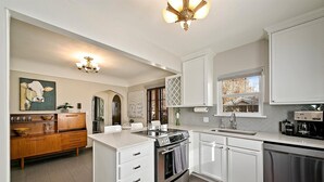 Una cocina moderna con armarios blancos, electrodomésticos de acero inoxidable y una isla central.