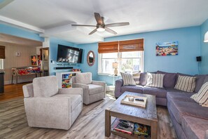 A living room with a ceiling fan, a TV, a sofa, a coffee table, and a bookshelf.