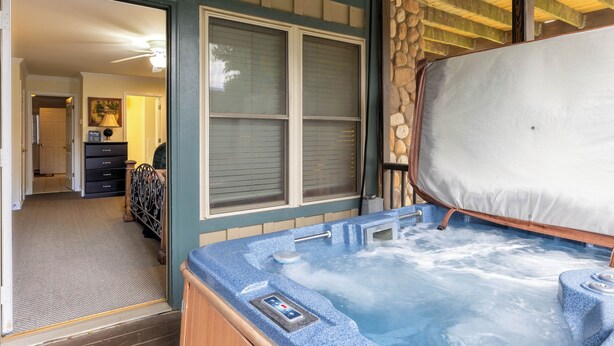 A hot tub with a control panel, a wooden deck, and a stone wall. - Sleeping Bear Condo - Downtown Helen, GA (Helen)