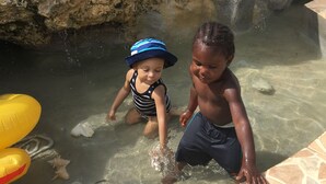 Un espace piscine avec une eau claire, des parois rocheuses et des jeux gonflables.