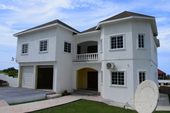 A two-story house with a garage, a balcony, and a satellite dish.