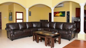 A living room with a brown leather sectional sofa, a coffee table, and a ceiling fan. - Plantation Villa 354 - Ocho Rios (St. Ann's Bay)