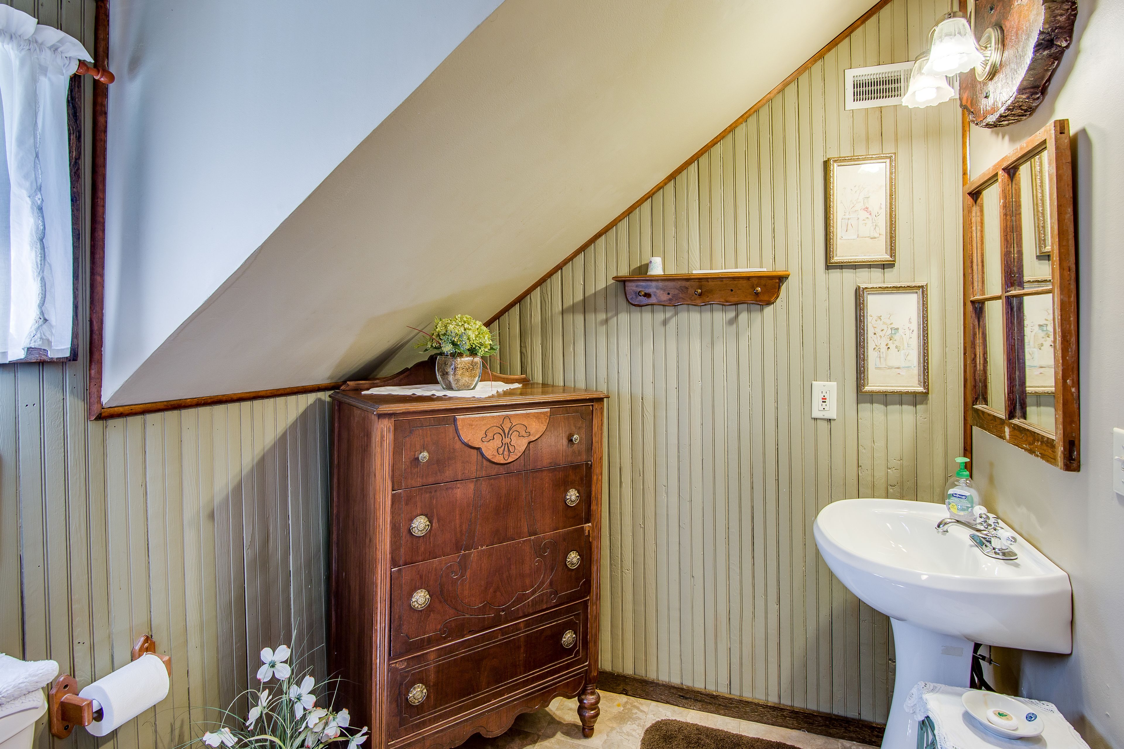 Une salle de bain avec une commode en bois, un lavabo blanc et un miroir.
