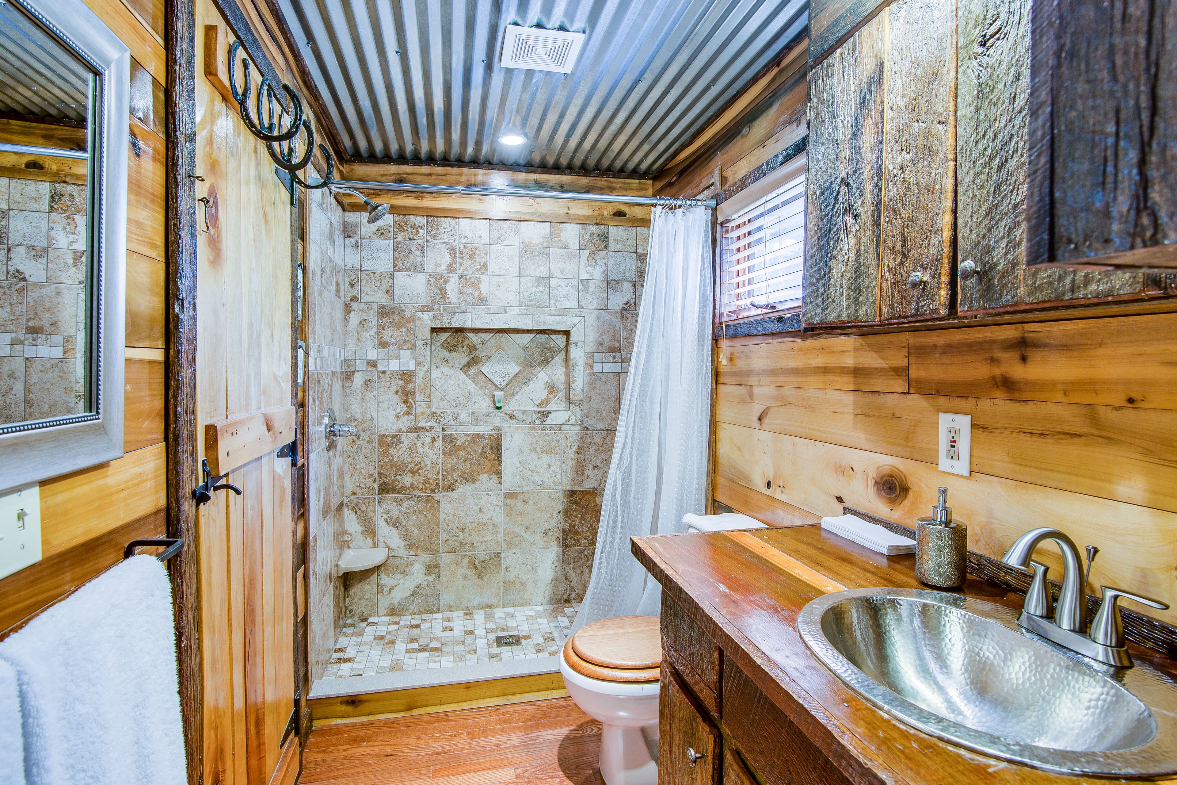 Een houten badkamer met douche, toilet en wastafel.