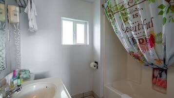 A bathroom with a white sink, a window, a shower curtain with floral patterns, and a towel rack.