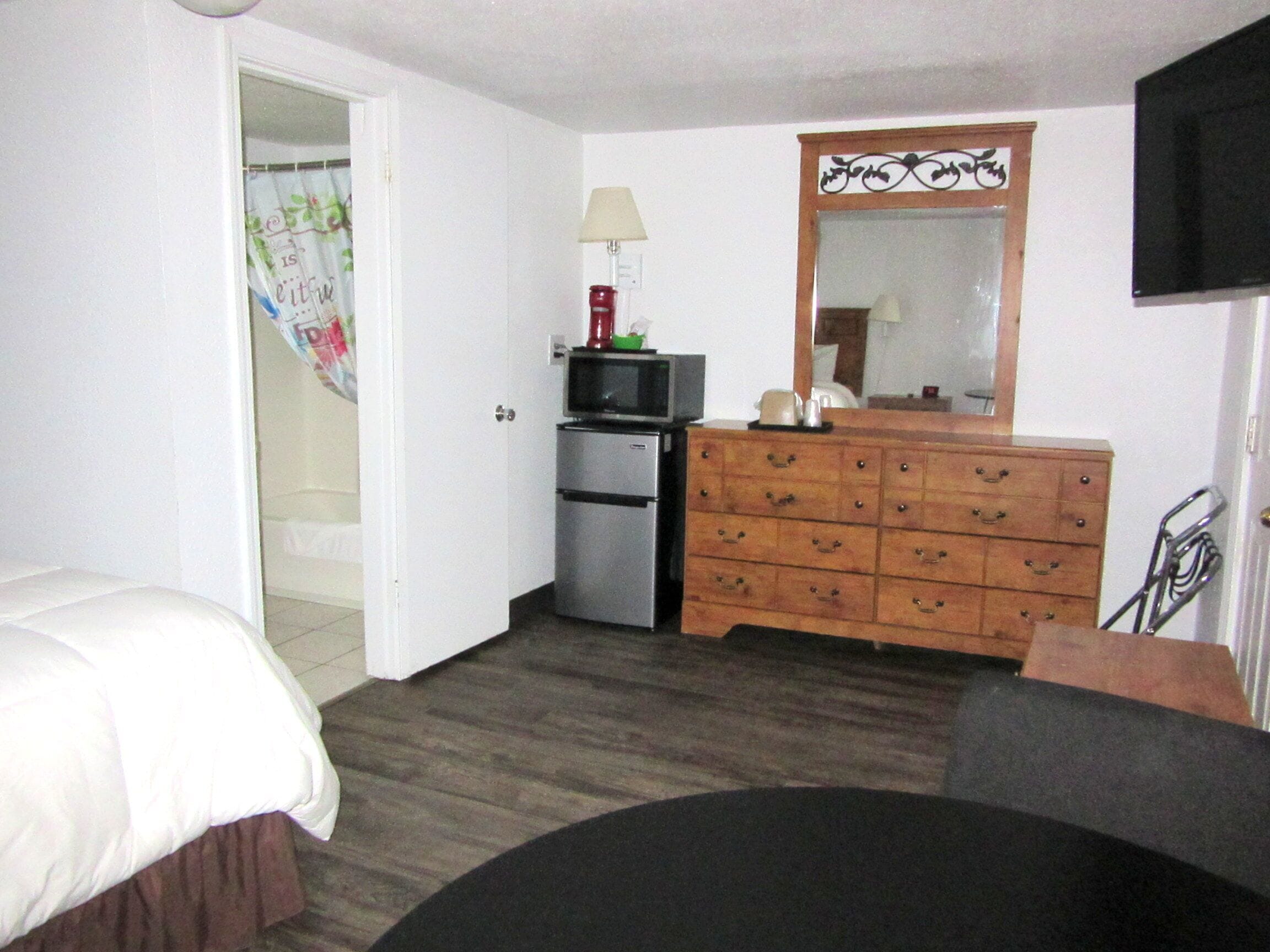 A hotel room with a bed, a dresser, a microwave, and a television.
