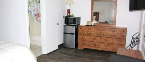 A hotel room with a bed, a dresser, a microwave, and a television.